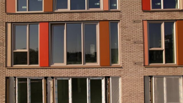 Closeup sideways and backwards aerial reveal of exterior facade of newly build apartment complex in Zutphen. Dutch engineering real estate social housing investment urban development