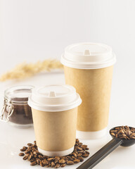 Two coffee to go cups and ground coffee in a glass jar