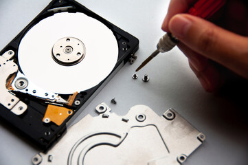 The abstract image of inside of hard disk drive with technician fixing using screw driver. Concept of data, hardware, and information technology.
