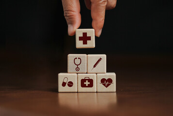 hand arranged wooden blocks stacked with health insurance health insurance icons for your health concept on a dark background.