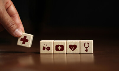 Hand arranged wooden blocks in the shape of a cube. with health medical icon, your health insurance on a dark background.