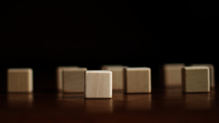 A prominent blank wooden block is placed in front of several blurred wooden blocks. on a dark background For text area copy area.