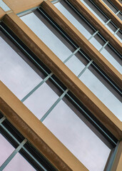 Obraz premium Vertical Low angle view of a building with brown wall claddings and tinted glass windows