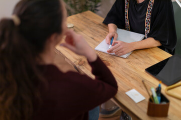 A female therapist in her office talking to a client to determine the best treatment for her health