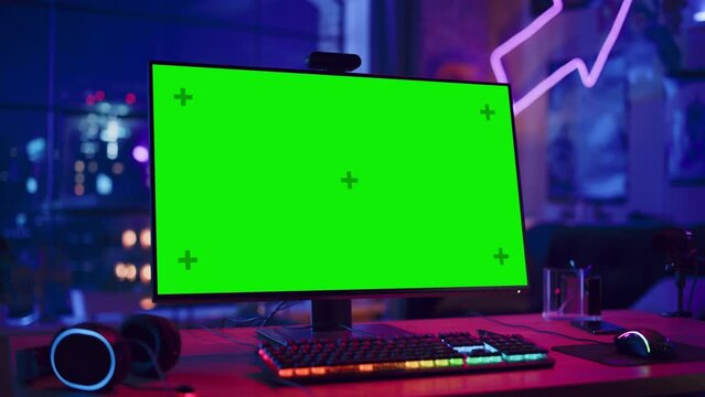 Gaming at Home: Empty Gaming Station with Player's Personal Computer with Green Screen Chroma Key Display Standing on a Wooden Desk in Stylish Loft Apartment with Neon Lights. Arc Shot.