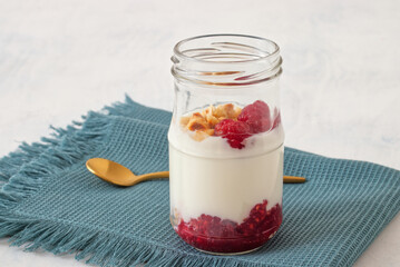 Healthy nutrition food, plain Greek yogurt, fresh raspberries and crushed hazelnuts on white background.