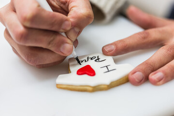 Woman writing sentences about decorated cookies in bakery