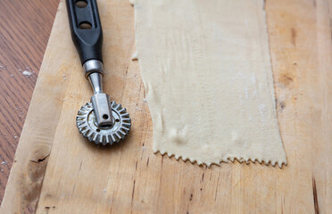 Dough and flour on wood, Homemade dough and pastry cutter wheel on kitchen table close up view