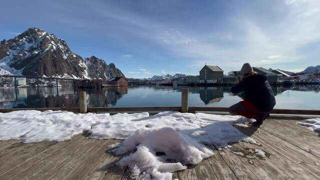 Young tourist taking a video of the scenery view inside Svolvaer Harbor on a Sunny day, Lofoten Island, Static low shot.