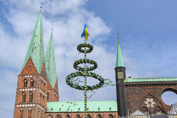 Maypole in the colors of Ukraine with peace doves between the towers of the Lubeck Marienkirche and...
