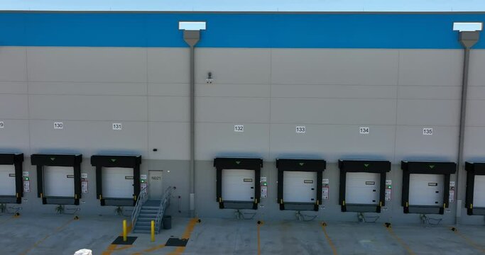 Warehouse distribution center logistics and freight theme. Garage bays for truck load and unload at dock. Numbered doors. Aerial truck shot.