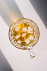 golden brown or amber liquor in stein glass with ice on white background shot from top down perspective