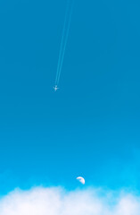 Airplane traveling across the blue sky with moon and clouds