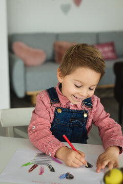 Cute boy, child in red shirt, drawing picture for Mothers day, little chicks on the table