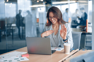 Confident deaf businesswoman communicating in video call with client at workplace in modern office.