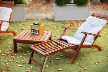 Lounge sunbed. Wooden garden furniture on grass lawn outdoor for relax. Backyard exterior. Wooden chairs  in autumn garden. Vintage radio on table. Two deckchairs on green summer lawn on picnic. 
