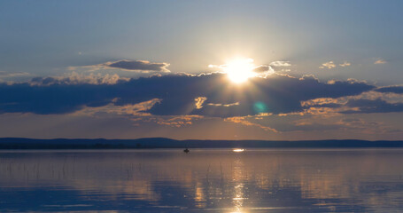 Sunset over lake. clouds. Water. San in the sky.