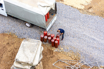 Combustible gas in red cylinders is loaded into tilt truck to deliver them to service of filling or exchanging cylinders