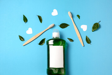 Mouthwash, two wooden bamboo eco friendly toothbrushes, green leaf, white hearts on blue studio background in studio with copy space for advertisement. Teeth hygiene, valentines day concept. Flat lay