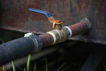 An old ball valve with a handle on a rusty tank
