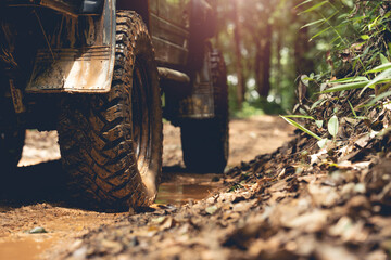 Part of an off-road vehicle on a dirt road with warm light. Adventure concept.Tire off-road on mud	 - obrazy, fototapety, plakaty