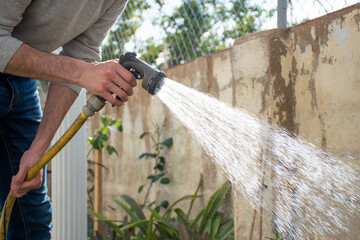 Man watering the home garden with a hose. Gardening. 