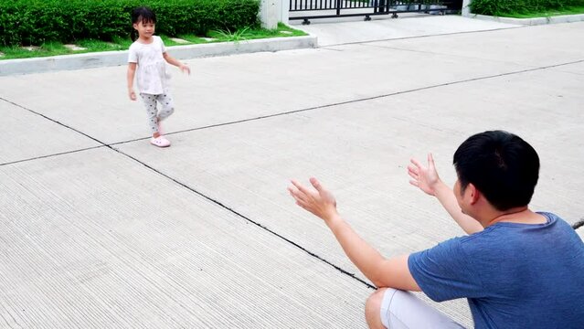 Father and daughter play in front the house street.So naughty child running on the road,dady try catching her,family together concept.
