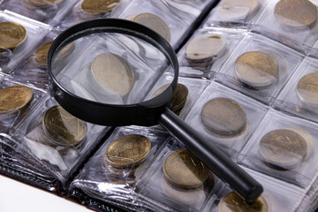 Magnifying glass on the background of an album with a collection of coins