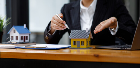 Mortgage loan Real estate broker agent presenting and consulting the customer to decision-making sign insurance form agreement, home model, concerning offer for and house insurance.