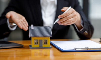 Mortgage loan Real estate broker agent presenting and consulting the customer to decision-making sign insurance form agreement, home model, concerning offer for and house insurance.