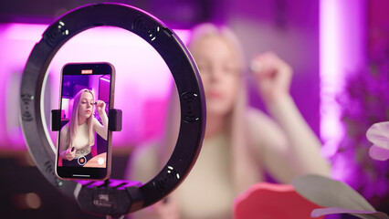 Female make up influencer record eyelashes care tutorial with smartphone - obrazy, fototapety, plakaty