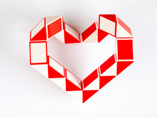 red and white bicolor magic snake Transformable twist puzzle in shape of heart isolated on white...