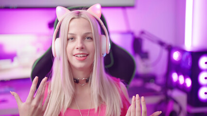 Cute blonde gamer girl with cat ear headphones in cyberspace interacting to fans © Video_StockOrg
