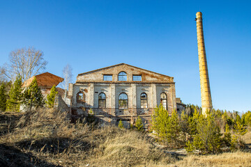 The ruins of an old industrial building with a rickety pipe, the concept of destroyed buildings