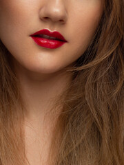 Fototapeta premium The macro photo of the closed female mouth. Chubby lips with red lipstick show a fashionable make-up and increase in lips. Cosmetology, Spa, cosmetics