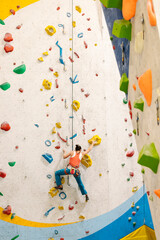 Fototapeta na wymiar Young Woman rock climbing indoors.