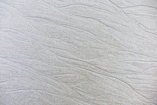 Sand background and texture. Wet beach sand texture after low tide. Sand with wave print. Ripple on the beach sand.