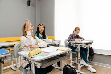 Ginger boy stretching up his hand during class at school