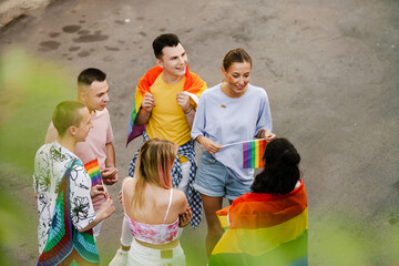 Young gay people smiling and holding rainbow flags during pride parade