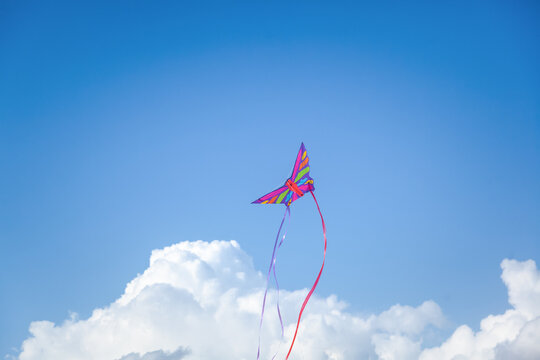 Summer vacation and travel concept. Bright kite in the blue sky with clouds