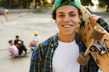 Hispanic boy smiling and holding skateboard at skate park