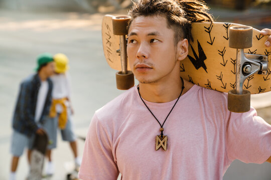 Asian boy holding skateboard while spending time at skate park - Powered by Adobe