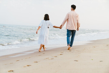 Fototapeta na wymiar Multiracial couple holding hands while walking on beach