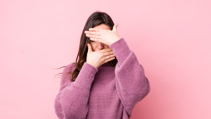 young pretty woman covering face with both hands saying no to the camera! refusing pictures or...