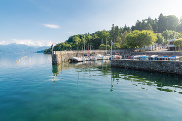 Fototapeta na wymiar Typical small harbor on a large lake in northern Italy. Lake Maggiore at the lakeside of the town of Ispra with moored boats. Summer landscape