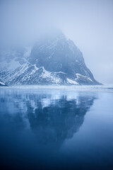 Reflection of a snow copped mountain on a beach during blue hour
