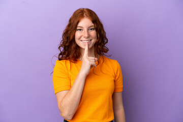 Teenager redhead girl over isolated purple background showing a sign of silence gesture putting...