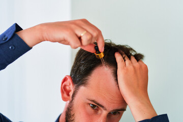 Man using essential vitamin oil serum to stimulate hair growth