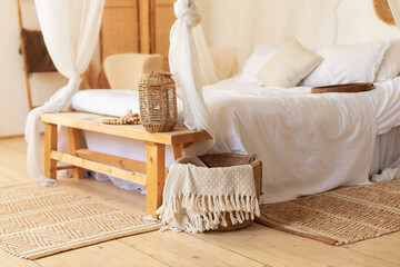 Cozy room with decoration and wisker basket with plaids. hygge decor at home. Scandinavian bedroom interior decoration with comfortable bed and pillows. Bed with flowing white curtains in boho style  © stock_studio