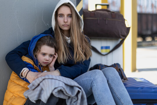 Depressed Ukrainian immigrants sitting and waiting at railway station.